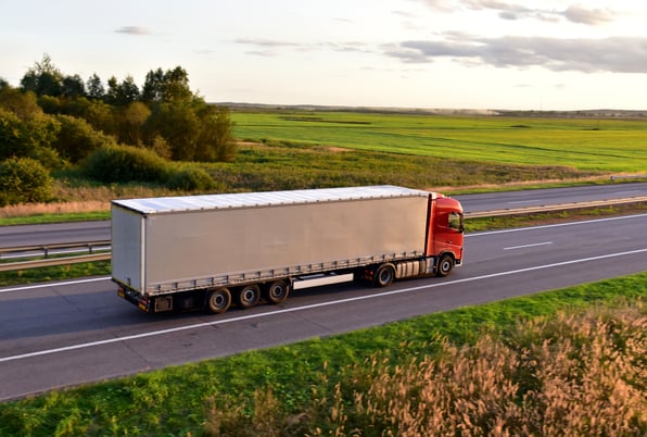 White commercial truck driving on an open country highway, representing 2026 commercial auto liability insurance market